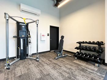 a gym with weights and cardio equipment in a corner of a room  at The Duo, University Place, WA 98466